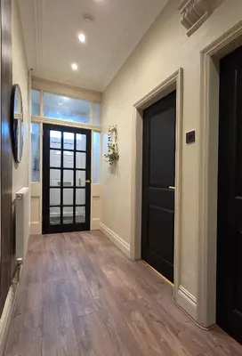 a hallway with a black door and wooden floors at 3 bedroom modern newly renovated house in Preston in Preston