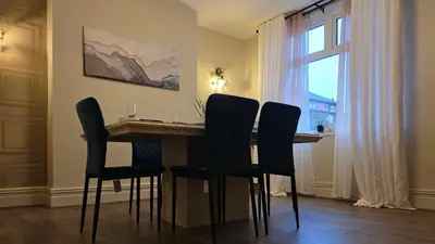 a dining room table with black chairs and a window at 3 bedroom modern newly renovated house in Preston in Preston