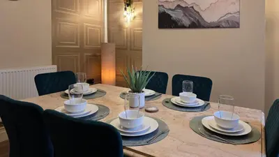 a wooden table with chairs and plates and cups on it at 3 bedroom modern newly renovated house in Preston in Preston