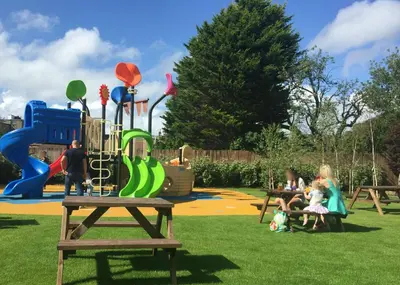 a group of people sitting in a park with a playground at The Morecambe Hotel in Morecambe