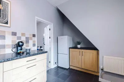 a kitchen with a white refrigerator and a staircase at St Helens Central, 2 Bed , Long Stay OFFERS, Contractors, Relocations, Families, Sleeps 4 Banner Street 10, St Helens in Saint Helens