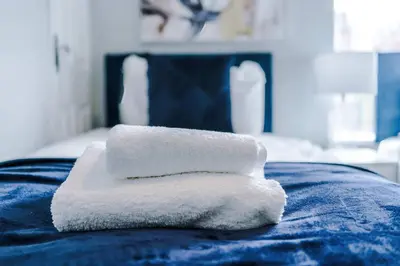 a stack of towels sitting on top of a bed at St Helens Central, 2 Bed , Long Stay OFFERS, Contractors, Relocations, Families, Sleeps 4 Banner Street 10, St Helens in Saint Helens