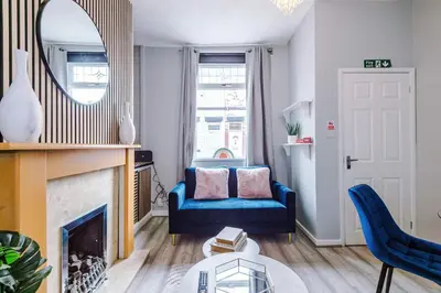 a living room with a blue couch and a mirror at St Helens Central, 2 Bed , Long Stay OFFERS, Contractors, Relocations, Families, Sleeps 4 Banner Street 10, St Helens in Saint Helens