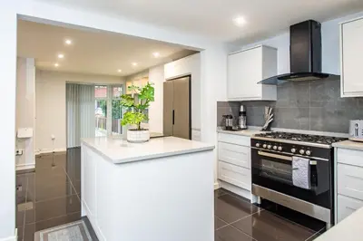a kitchen with white cabinets and a black stove at Superb Location Stunning Luxury 4 Bedroom House in Liverpool