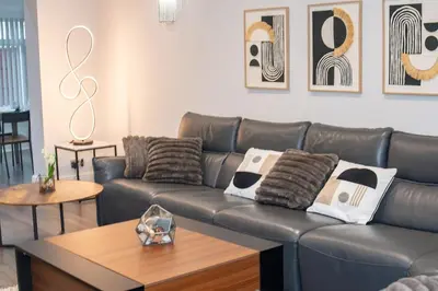 a living room with a leather couch and a table at Superb Location Stunning Luxury 4 Bedroom House in Liverpool