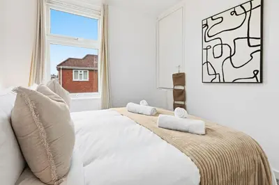 a white bedroom with a large bed with a window at Warm and Cosy Home at L6 Sleeps 5 in Liverpool