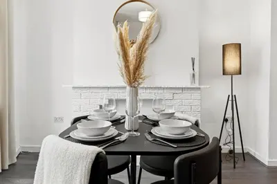 a dining room with a black table and a mirror at Warm and Cosy Home at L6 Sleeps 5 in Liverpool