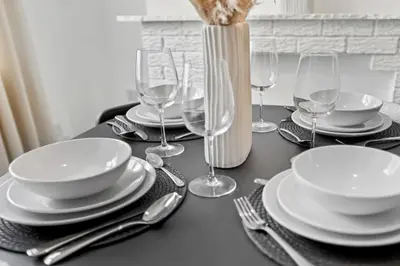 a table with plates and wine glasses and a vase at Warm and Cosy Home at L6 Sleeps 5 in Liverpool