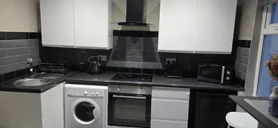 a kitchen with white cabinets and a washer and sink at Cozy 1 bed apartment Blackpool in Blackpool