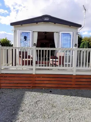 a screened in porch with a white fence and chairs at Carol & Nick's holiday home in Heysham