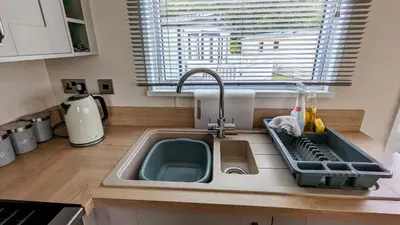 a kitchen counter with a sink and a window at Carol & Nick's holiday home in Heysham