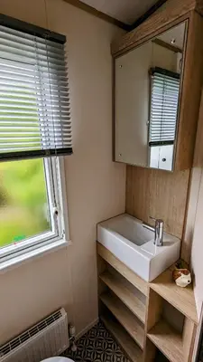 a bathroom with a sink and a mirror and a window at Carol & Nick's holiday home in Heysham