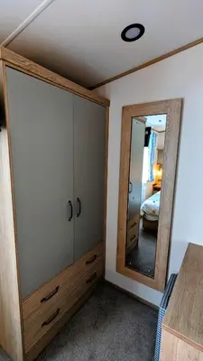 a bedroom with a large mirror and a dresser at Carol & Nick's holiday home in Heysham