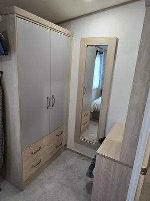 a bedroom with a large dresser and a mirror at Carol & Nick's holiday home in Heysham