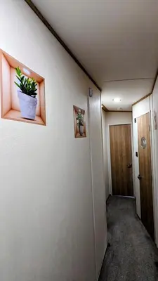 a hallway with a door and a potted plant on a wall at Carol & Nick's holiday home in Heysham