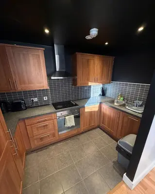 a kitchen with wooden cabinets and a stove top oven at 2-Bed City View with Balcony Liverpool by StaySavvy Accommodation in Liverpool
