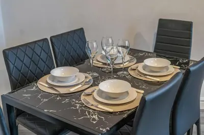 a black table with plates and wine glasses on it at Spacious City Flat - 2 Bedrooms - Sleeps 7 in Liverpool
