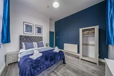a bedroom with a large bed with blue walls at Spacious City Flat - 2 Bedrooms - Sleeps 7 in Liverpool