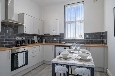 a kitchen with a table with plates and wine glasses at Comfortable 2BR Flat - Sleeps 6 - Ideal City Stays in Liverpool