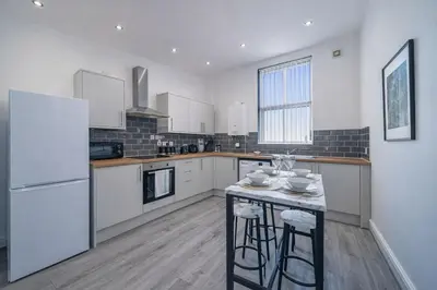 a kitchen with a white refrigerator and a table with stools at Comfortable 2BR Flat - Sleeps 6 - Ideal City Stays in Liverpool