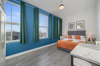 a bedroom with blue walls and a bed with orange sheets at Large 2-Bedroom Flat Sleeps 7 - Perfect for Groups in Liverpool