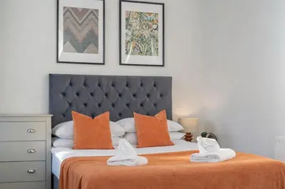 a bedroom with a bed with an orange blanket at Large 2-Bedroom Flat Sleeps 7 - Perfect for Groups in Liverpool