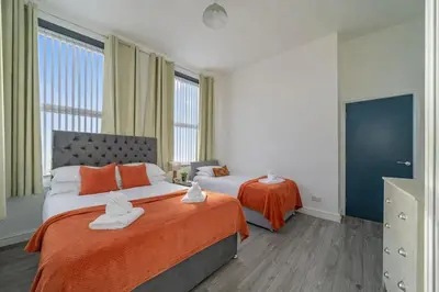 a bedroom with two beds with orange sheets at Large 2-Bedroom Flat Sleeps 7 - Perfect for Groups in Liverpool