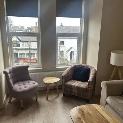 a living room with two chairs and a couch and two windows at King's Haven in Southport