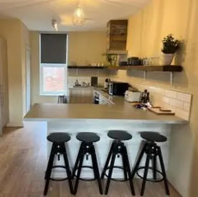 a kitchen with a counter with four bar stools at King's Haven in Southport
