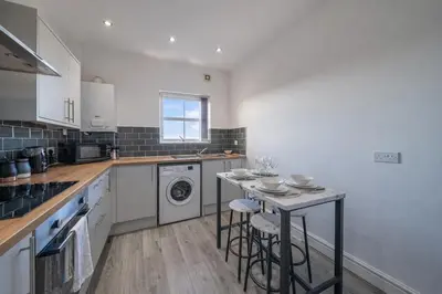 a kitchen with a table and a dishwasher at 2BR Flat - 4 Beds Sleeps 7 - Trinity Vaults in Liverpool