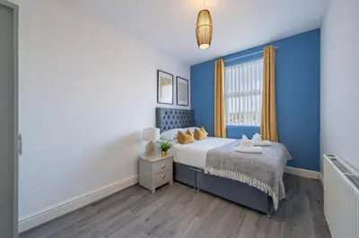 a blue bedroom with a bed and a window at 2BR Flat - 4 Beds Sleeps 7 - Trinity Vaults in Liverpool
