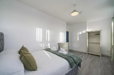 a bedroom with a large white bed with a green blanket at Family-Friendly 2BR Flat - Sleeps 7 in Liverpool
