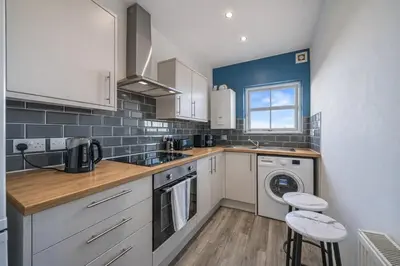 a kitchen with white cabinets and a washer and dryer at Family-Friendly 2BR Flat - Sleeps 7 in Liverpool