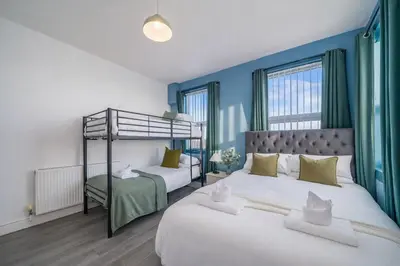 two beds in a bedroom with blue walls at Family-Friendly 2BR Flat - Sleeps 7 in Liverpool