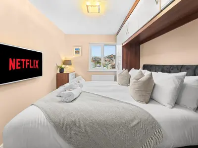 a bedroom with a large white bed with a tv on the wall at Central Chorley Home Free Parking Fast Wi-Fi in Chorley