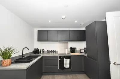 a kitchen with black cabinets and a sink at Spacious 2 Bed Apartment in Central Liverpool in Liverpool