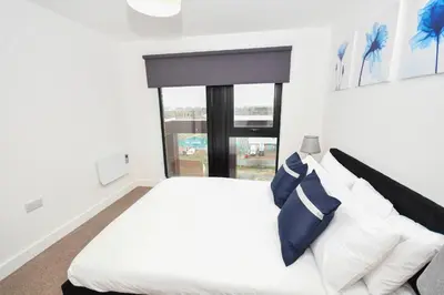 a bedroom with a white bed with blue and white pillows at Spacious 2 Bed Apartment in Central Liverpool in Liverpool