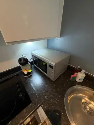 a microwave sitting on a counter in a kitchen at City View Studio Apartment Liverpool by StaySavvy Accommodation in Liverpool