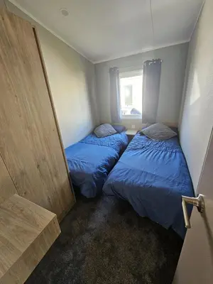 two beds in a small room next to a window at Crozzer's Place in Heysham