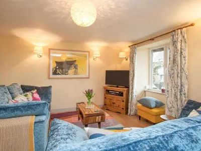 a living room with a blue couch and a tv at Yan Cottage - Uk43540 in Spark Bridge