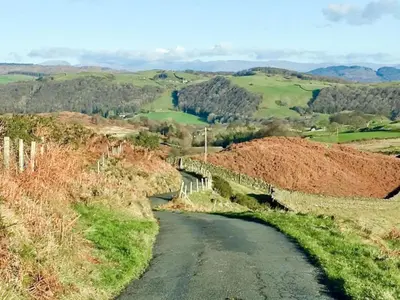 a winding road in the hills with a bridge at Yan Cottage - Uk43540 in Spark Bridge