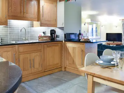 a kitchen with wooden cabinets and a table at Yan Cottage - Uk43540 in Spark Bridge