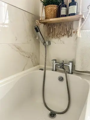 a bathroom with a bath tub with a faucet at Preloved stylish home Wi-Fi Double driveway in Kirkby