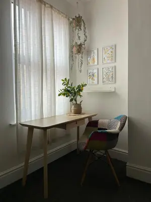 a table and a chair with a potted plant on it at Music touch house Free Parking WIFI Close to Anfield stadium in Liverpool