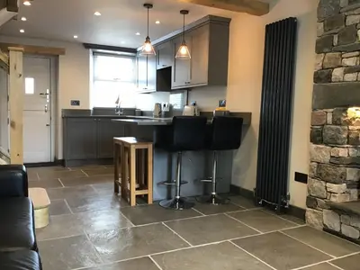 a kitchen with a bar and a stone wall at Tastefully Renovated Cottage in Ulverston in Ulverston