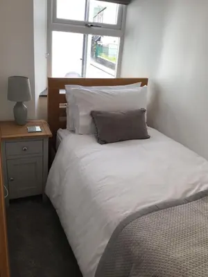 a bed with white sheets and pillows next to a window at Tastefully Renovated Cottage in Ulverston in Ulverston