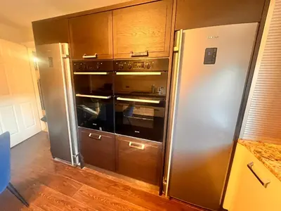 a kitchen with a stainless steel refrigerator and wooden cabinets at Casa del Mare-Beachfront House in Morecambe