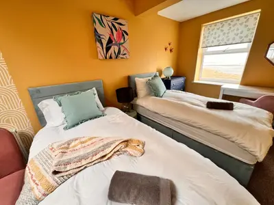 two beds in a room with a dog laying on them at Casa del Mare-Beachfront House in Morecambe