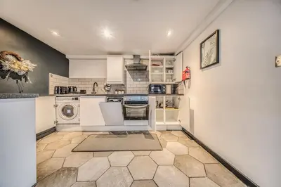 a kitchen with white cabinets and a washer and dryer at Premium Central Liverpool Apartment in Liverpool