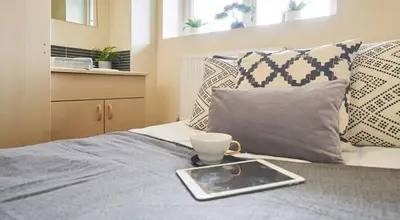 a tablet on a bed with a cup on it at For Students Only St Andrews Gardens in Liverpool in Liverpool